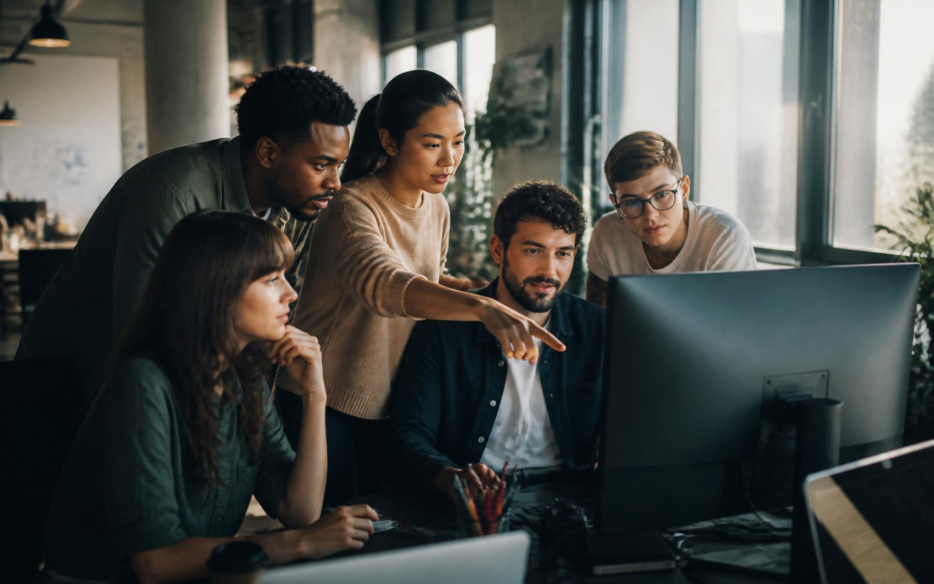 Nexion team collaborating around a monitor in a modern office